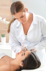 Fototapeta premium Young woman undergoing eyebrow correction procedure in beauty salon