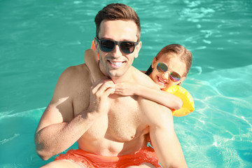 Father with little girl in swimming pool on summer day