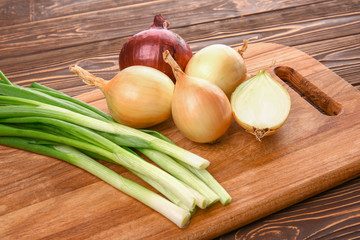 Cutting board with fresh onion on wooden background