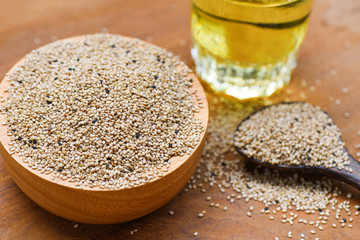 sesame seeds in wooden bowl and spoon with Sesame oil in glass