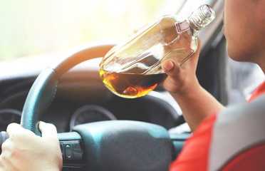 drunk driver concept - Man holding with alcohol bottle in hand and drive drink alcohol in car