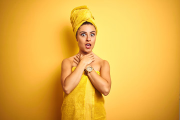 Young beautiful woman wearing towel after shower over isolated yellow background shouting and...