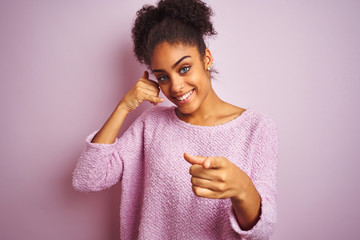 Young african american woman wearing winter sweater standing over isolated pink background smiling...