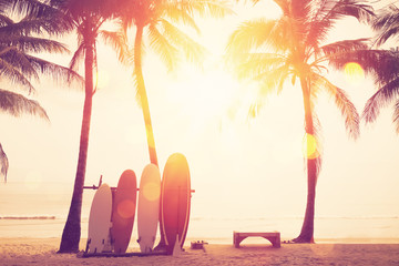 Surfboard and palm tree on beach background.