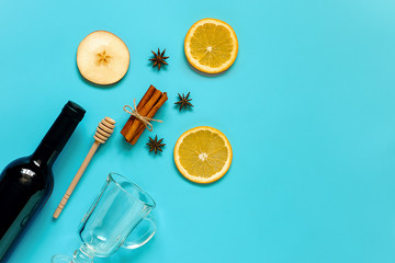 Mulled Wine Ingredients, still life on blue background. Bottle of wine, cinnamon sticks, slices of orange, apple, anise and mug. Concept culinary recipe Creative Top view Flat lay Copy space