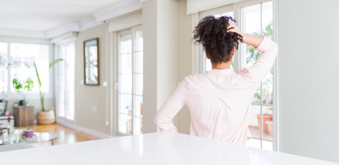 Wide angle of beautiful african american woman with afro hair Backwards thinking about doubt with hand on head