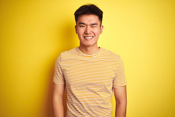 Young asian chinese man wearing t-shirt standing over isolated yellow background winking looking at the camera with sexy expression, cheerful and happy face.