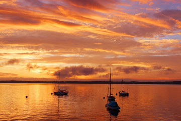 Fototapeta na wymiar Beautiful marine after sunset background. Amazing summer evening landscape with group of drifting yachts on a lake Mendota during spectacular sunset. Bright sky reflects in the lake water.
