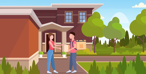 woman receiving order from man courier with backpack and paper package express food delivery from shop or restaurant concept modern house building exterior flat horizontal full length