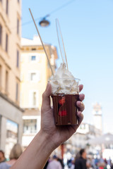 Hand holding a cup of Strawberry with chocolated and whipped cream