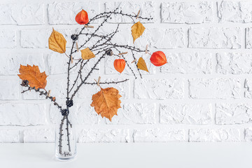 Autumn creative bouquet of branches with yellow leaves on clothespins in vase on table background white brick wall Copy space Minimal style. Template for postcard, text, design Concept Hello autumn