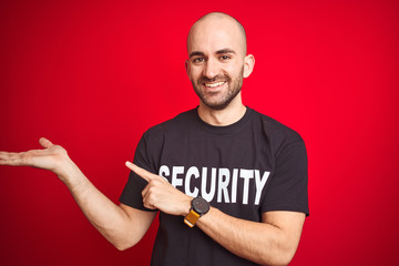 Young safeguard man wearing security uniform over red isolated background amazed and smiling to the...