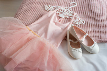 Little shoes and pink dress on a bed in kid bedroom. kid prepare to party. 