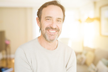 Obraz premium Handsome middle age man smiling looking at the camera at home