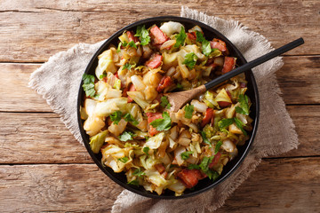 Appetizer of fried white cabbage with bacon closeup on a plate on a table. horizontal top view