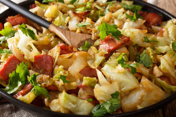Stir fried cabbage with crispy bacon closeup on a plate on a table. horizontal
