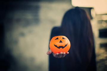 Pumpkin carved smiling face holding a protruding front with a woman ghost  background, Jack O Lantern Halloween.