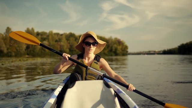 Woman Exploring Calm River By Canoe.Close Up Girl In Kayak.Pretty Woman In Hat And Sunglasses Kayaking On Lake At Sunset And Holds Oar.Girl Traveler In Life Vest Sing On Lake At Sunset And Holds Oar. 