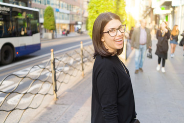 Beautiful young brunette woman smiling excited walking down the city streets, happy and confident expression standing outdoors at the town