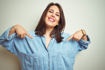 Young beautiful brunette woman wearing casual blue denim shirt over isolated background looking...