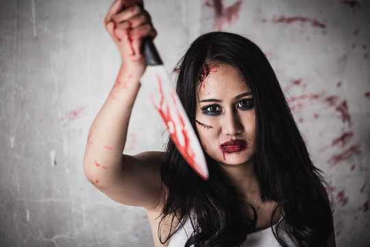 Horror Picture of a female killer at bloody knife honding hand with scary face.