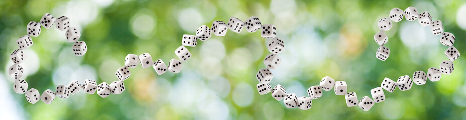 Dice connected in a chain on a blurred green background with bokeh .