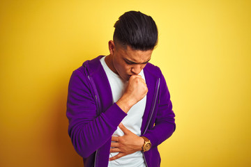 Young brazilian man wearing purple sweatshirt standing over isolated yellow background feeling...