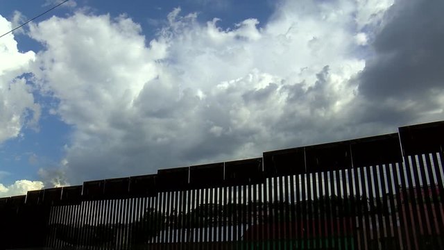Stunning timelapse of the Arizona desert border wall between US and Mexico, among politics and government, where clouds roll over the fence against a deep blue sky