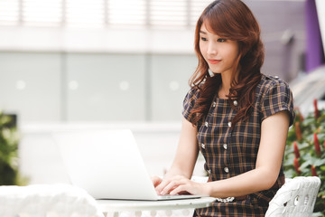 Beautiful business asian woman using a laptop computer on the table in outdoor cafe.
