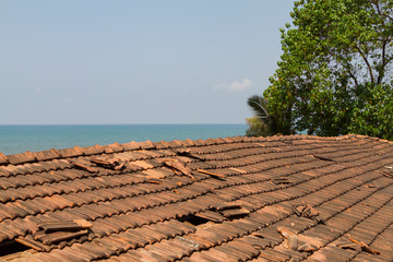 Broken old terracotta tile on a roof on sea background. Traditional cover in India, GOA. Summer time.