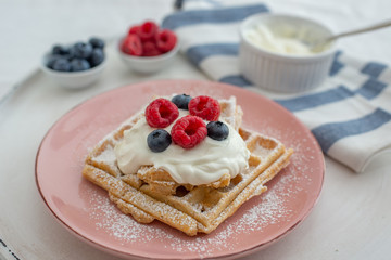 Tasty Belgian waffles with clotted cream and berries on plate