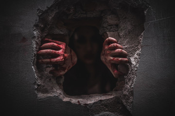 Halloween holiday, Horrible scary zombie with bloody hands is climbing in abandoned house. © Sumala