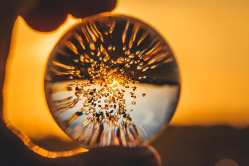 Crystal ball with grains of sand against the backdrop of the setting sun