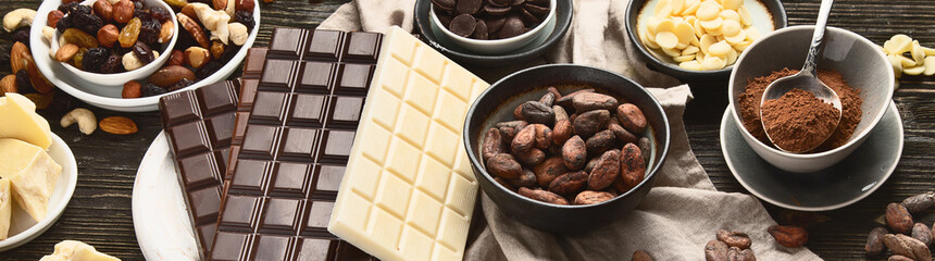 Dark bitter, milk and white chocolate,  cocoa butter, cacao powder and beans on wooden table.