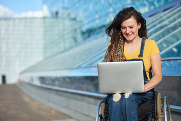 happy cute businesswoman in wheelchair working using a laptop, disability overcoming concept....