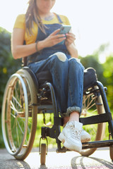 young attractive woman in wheelchair texting with her mobile phone, disability and employment concept. close up cropped photo. blurred background. free time, spare time