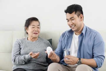 Asian man giving medicine to his mother, lifestyle concept.