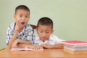 Two boys, reading a book, educating themselves