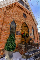 Face of a loal church. Early 1900's brick contruction. Christmas wreathes on the two front doors. Blue skies & white clouds.