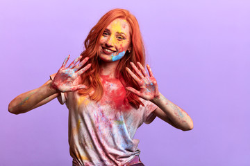 positive hipster girl shows both palms smeared with multicolored powder, Arrival of spring, close up portrait, isolated violet background, studio shot