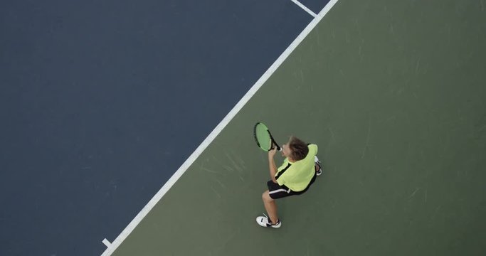 OVERHEAD CRANE Young Caucasian teenager male tennis player serving during a game or practice. Slow motion, 4K UHD RAW graded footage