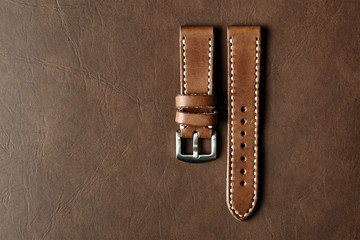 Dark brown leather watch strap with stainless buckle on leather background, Craft and handmade watch bracelet, Luxury classic and vintage style.