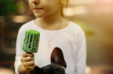 Toddler girl eating green ice-cream in park