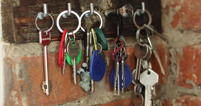 Female hand hangs on a hook a bunch of keys not a brick wall