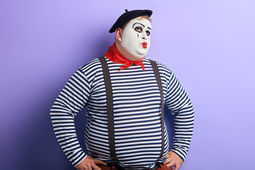 puzzled clown keeping hands on the hips looking up.. solving problems. copy space. young plump man...
