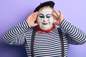 funny man entertaining children during the party, mime having fun, making faces. isolated blue background