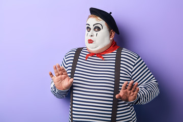 funny plump mime in stiped clothes asking not to worry, scared clown doesn't want to perform on stage