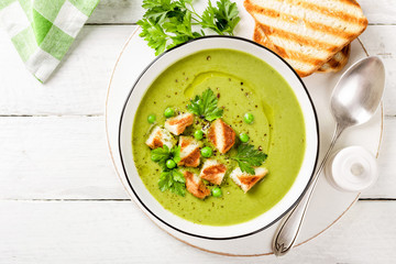 Pea soup. Green pea puree soup in a bowl served with grilled toasts, top view