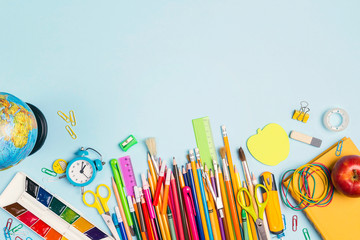 Back to school concept with school supplies and copy space on blue background.