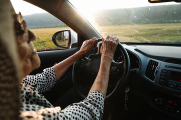 Old woman holds hands on wheel